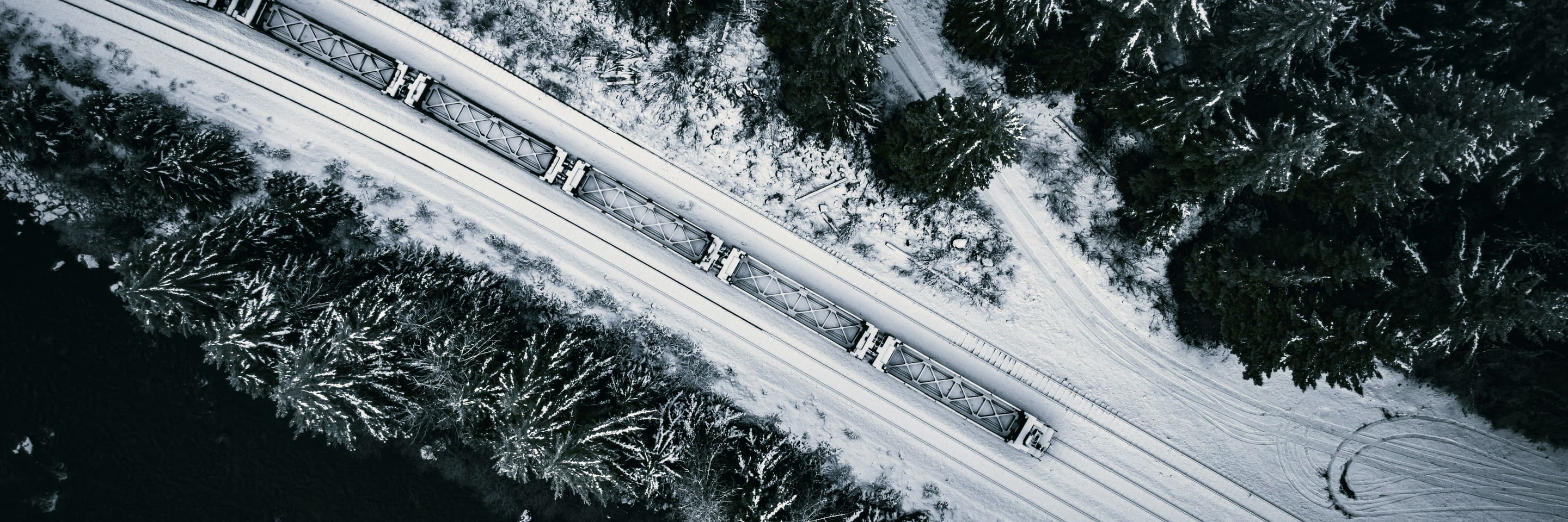 A freight train running through snow-covered forest in northern British Columbia, seen from above.