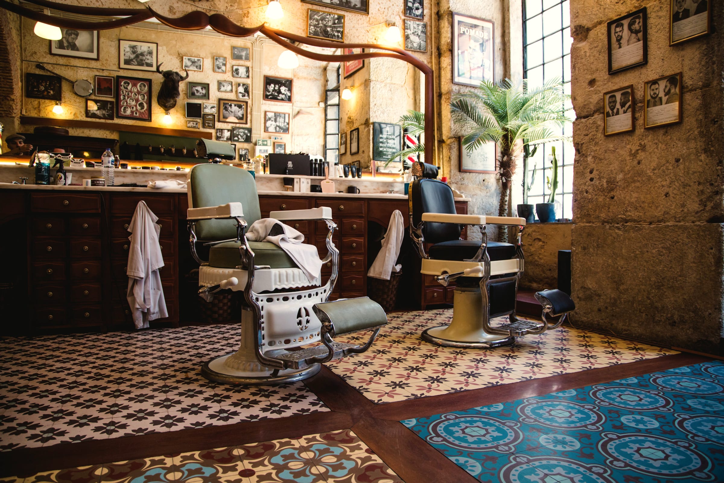 A barbershop interior, two vintage chairs waiting under warm lamps and framed pictures.