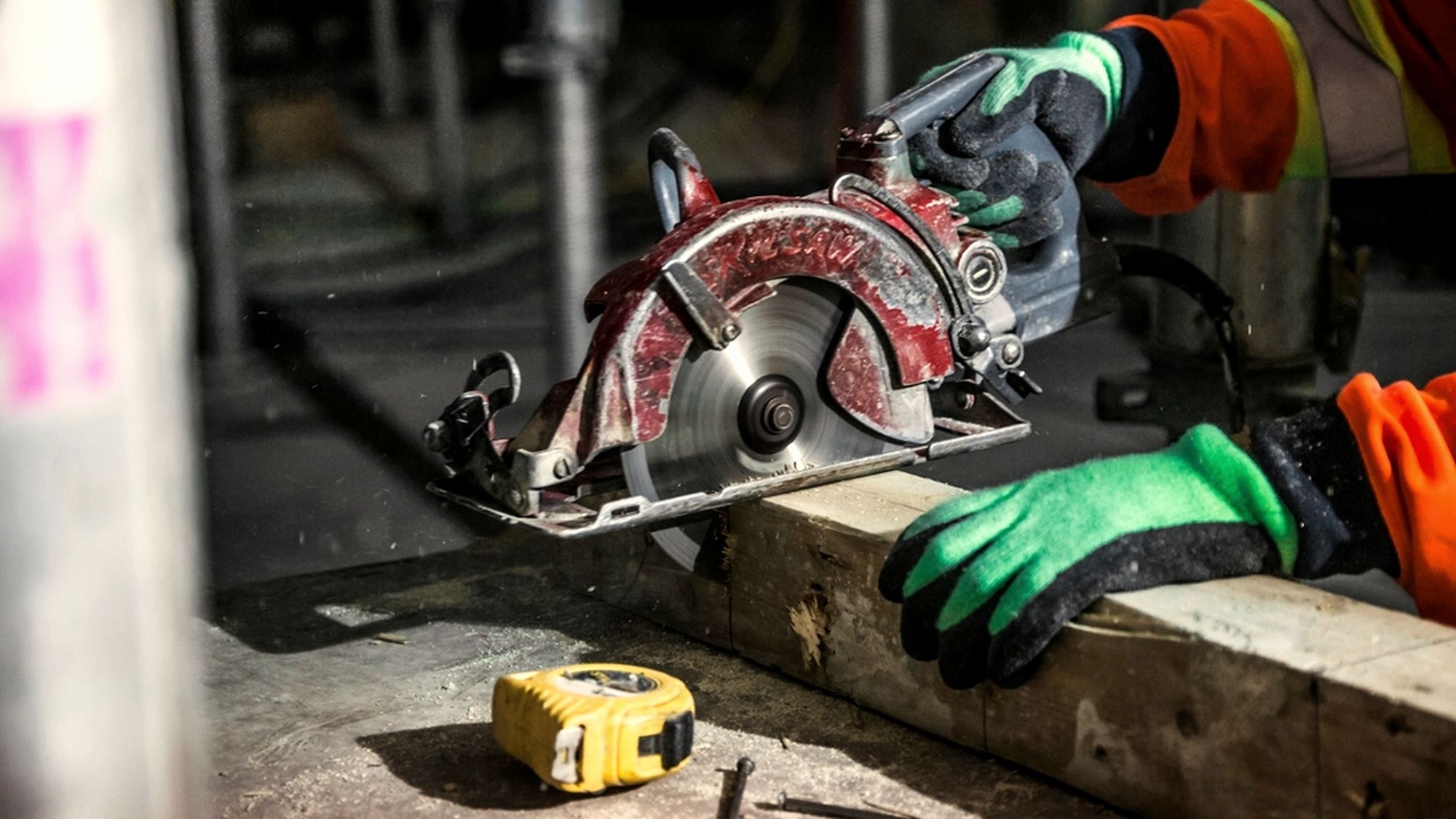 A tradesperson cutting framing lumber with a circular saw on a job site.
