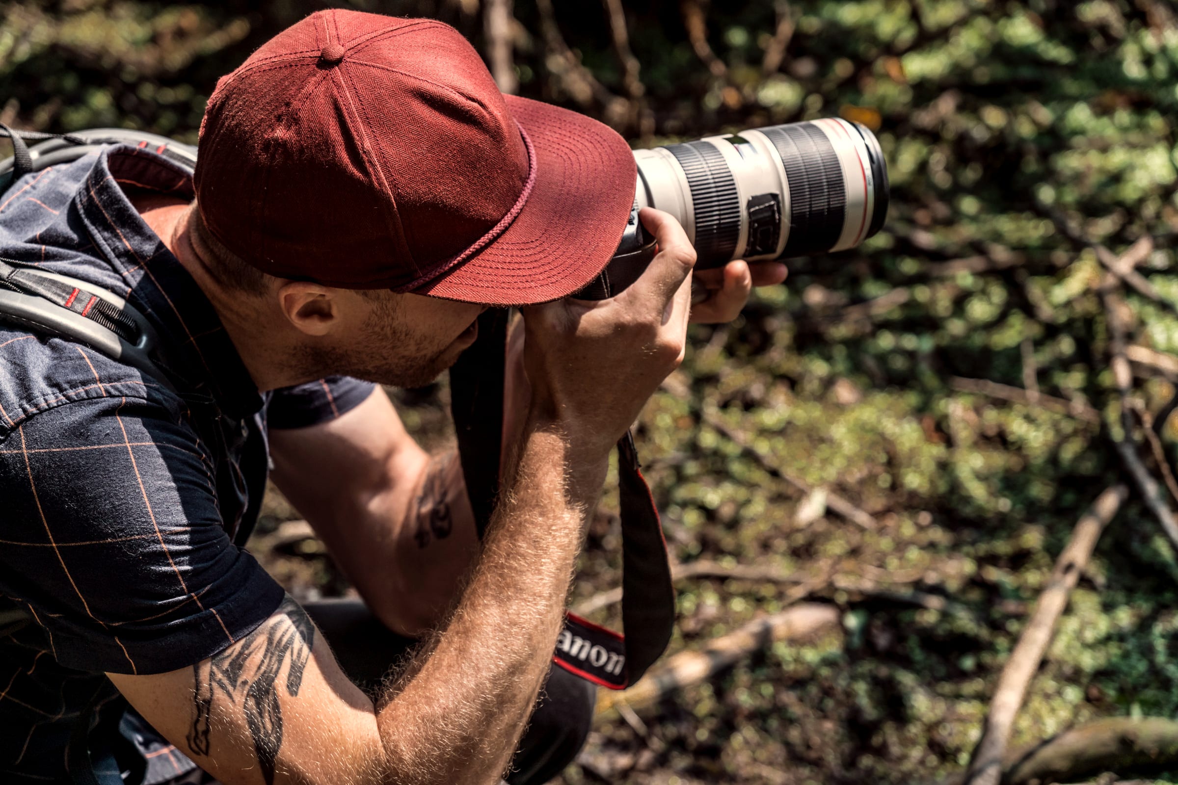 A photographer crouched low in the field, shooting with a long lens.